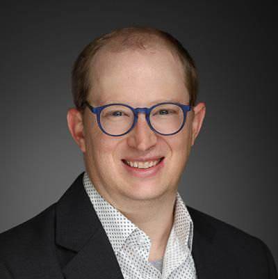 This is meaningful because it shows my professional look—confident and approachable in a dark suit, blue glasses, and light hair.